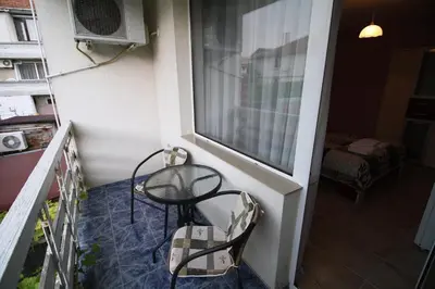 a balcony with a table and chairs and a window at Zoya Guest House in Ravda