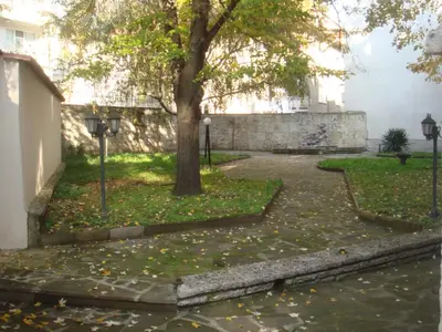 a tree and a sidewalk with leaves on the ground at Citadel Guest House in Varna City