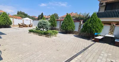 a courtyard with a fence and trees and a bench at Sineva Guest House in Ravda