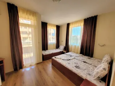 a bedroom with two beds and two windows at Guesthouse Iceberg in Ravda