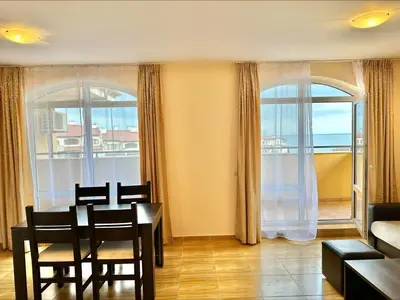 a living room with a table and chairs and windows at Menada Sky Dreams Apartments in Sveti Vlas