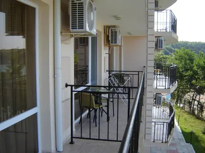 a balcony of a building with a table and chairs at Вила Лазурен бряг in Chernomorets
