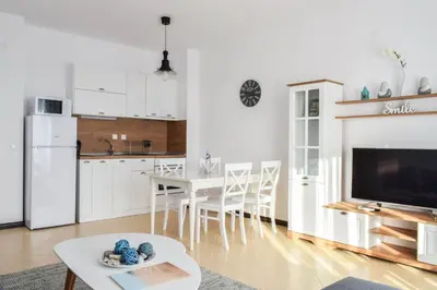 a kitchen and living room with a table and a tv at Oasis Resort Lozenets in Lozenets