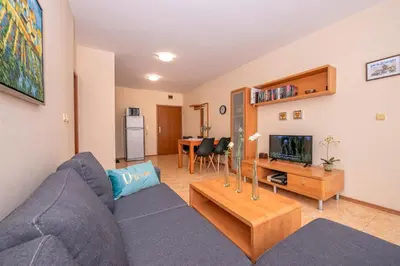 a living room with a blue couch and a tv at Elit 4 Apartments in Sunny Beach