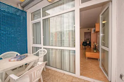 a dining room with a table and chairs and a large window at Elit 4 Apartments in Sunny Beach