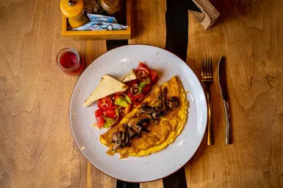 a plate of food with an omelet and vegetables on a table at Utopia Forest in Burgas City