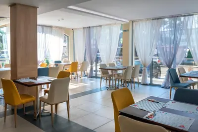 a restaurant with tables and chairs and windows at Belvedere Hotel - All inclusive in Primorsko