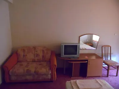 a living room with a chair and a desk with a television at Hotel Amigos in Obzor