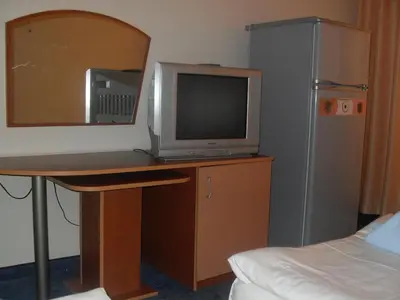 a room with a desk with a computer and a refrigerator at Hotel Amigos in Obzor