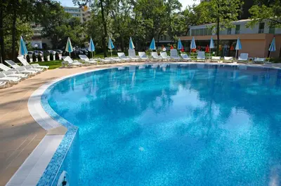 a large swimming pool with lounge chairs and umbrellas at Hotel Yunona - All Inclusive in Sunny Beach