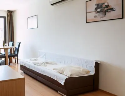 a bed in a room with a table and chairs at Seaside Garden Apartment with 2 BR for up to 5 pax in Sunny Beach