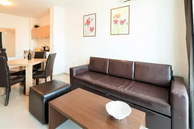 a living room with a brown leather couch and a table at Seaside Garden Apartment with 2 BR for up to 5 pax in Sunny Beach