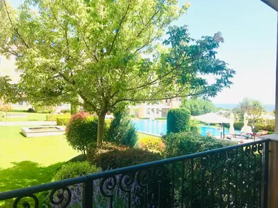 a balcony with a tree and a swimming pool at Apartments in complex ATIA RESORT in Chernomorets