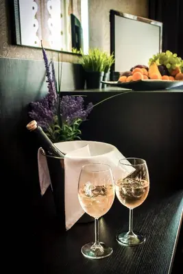 two glasses of wine on a table with a basket of flowers at Central Plaza in Pomorie