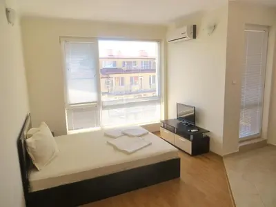 a bedroom with a bed and a television and a window at Apartments in Azalia 2 Complex in Nesebar
