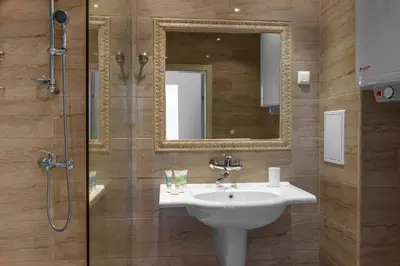 a bathroom with a sink and a shower with a mirror at Lily Beach Resort in Sozopol