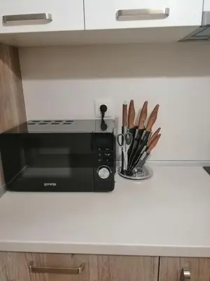 a kitchen counter with a black microwave and some knives at Sunny in Burgas City