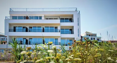a white building with blue balconies and flowers at JI HOTEL in Sozopol