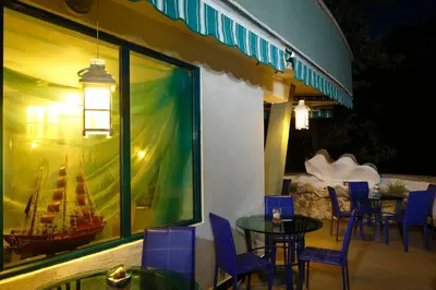 a patio with a table and chairs and a boat in a window at Elmar Hotel in Kiten