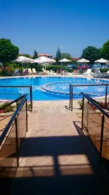 a large swimming pool with blue water and umbrellas at Sozopoli Hills Simeonov Apartments in Sozopol