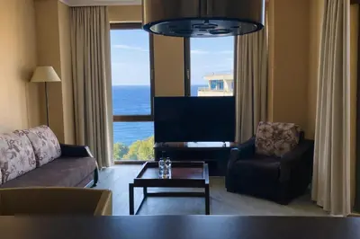 a living room with a couch and a chair and a television at ROYAL BEACH - Modern & Private Apartments in center Sunny Beach in Sunny Beach