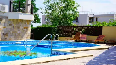 a swimming pool with chairs next to a building at Комплекс Бяла Виста до Плажа - Complex Byala Vista near the beach in Byala