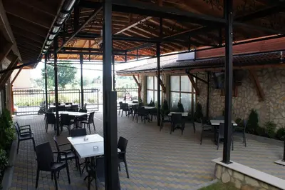 an empty restaurant with tables and chairs and windows at MM Complex Dimitrovi in Primorsko