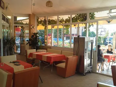 a restaurant with tables and chairs and people sitting at tables at Krasi Hotel in Ravda
