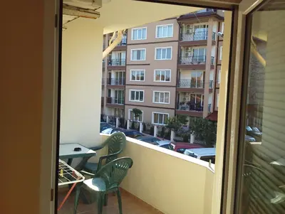 a balcony with chairs and a table and a building at Krasi Hotel in Ravda