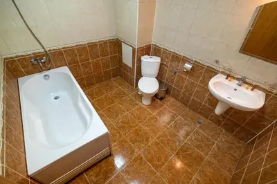 a bathroom with a tub and a toilet and a sink at Adamo Hotel in Varna City