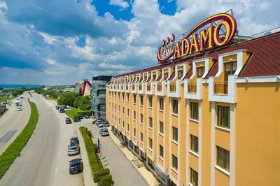 a yellow building with a sign on top of it at Adamo Hotel in Varna City