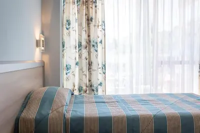a bedroom with a bed and a window with curtains at Hotel Longosa - All Inclusive in Sunny Beach