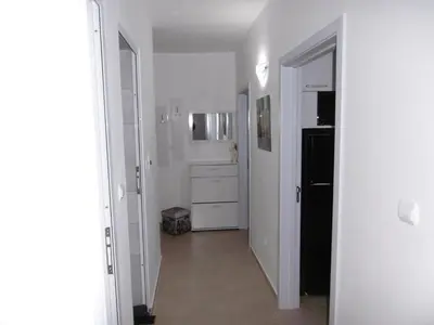 a hallway with a white kitchen with a black refrigerator at Апартамент Жекови in Tsarevo