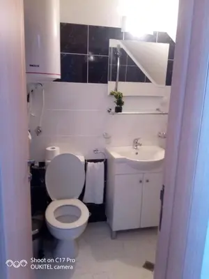 a bathroom with a white toilet and a sink at Guest house Veneta in Sozopol