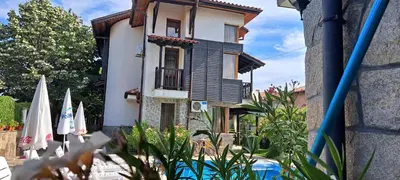 a house with blue shutters and a yard with umbrellas at Sani Holiday Village in Sozopol