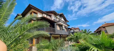 a building with palm trees in front of it at Sani Holiday Village in Sozopol
