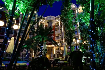 a hotel at night with tables and umbrellas at Sweet Homes 6 Apartments in Sunny Beach
