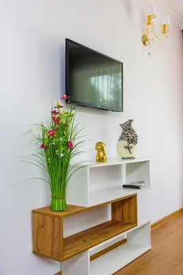 a television on a white shelf with a vase of flowers at Sweet Homes 6 Apartments in Sunny Beach