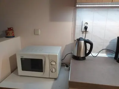 a microwave sitting on top of a counter with a kettle at Апартамент Термите in Varna City