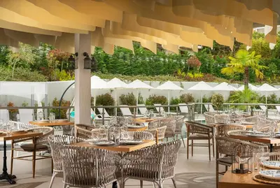 a restaurant with wooden tables and chairs and white umbrellas at Siena Premium Retreat in Lozenets