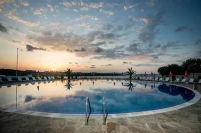 a large swimming pool with chairs and a sunset at Arapya Sun Resort in Arapya