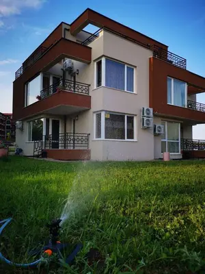 a house with a fire hydrant in the grass at Niko's Apartments Deluxe in Nesebar