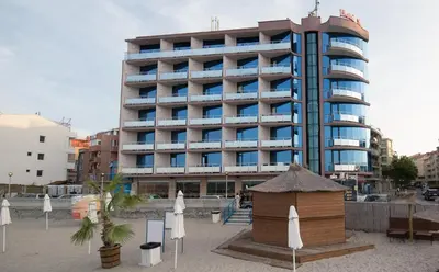 a large building with umbrellas in front of it at Hotel Sunny Bay Pomorie in Pomorie