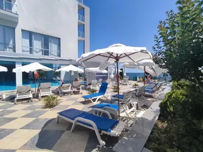 a group of chairs and umbrellas next to a pool at Moonlight Hotel - All Inclusive in Sveti Vlas