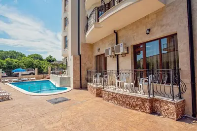a house with a swimming pool and chairs next to a building at Hotel Santa Maria in Obzor