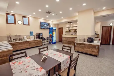 a restaurant with a table and chairs and a kitchen at Hotel Santa Maria in Obzor