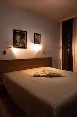a bedroom with a bed with two lights on the wall at Kalypso Hotel in Primorsko