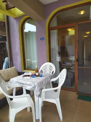 a table with two white chairs and a bottle on it at Гардън Бийч - НЕДЯЛКОВИ in Sozopol