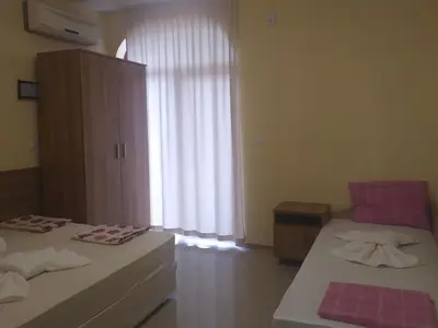 a room with two beds and a large window at Гардън Бийч - НЕДЯЛКОВИ in Sozopol