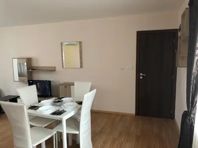 a dining room table with white chairs and a black door at Palace De Luxe - Apartments in Pomorie